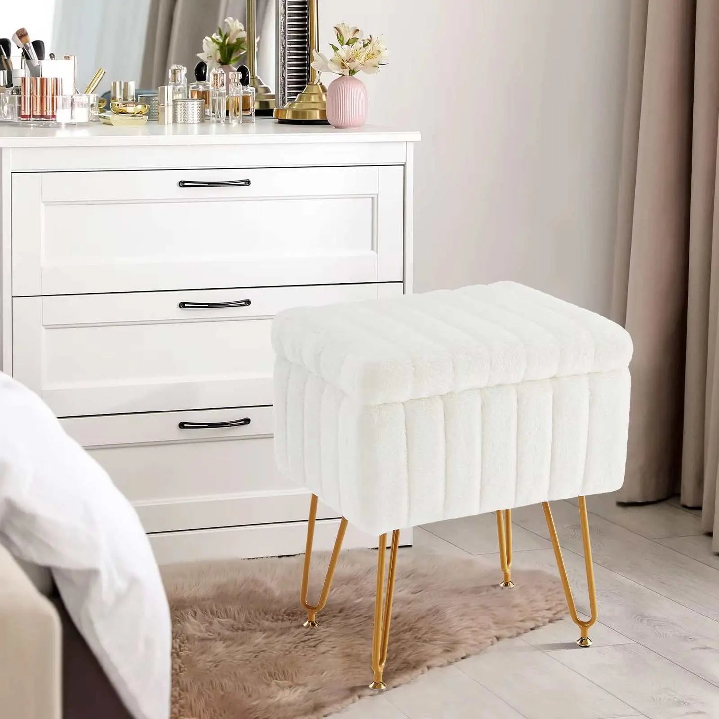 White faux fur living room storage stool with gold metal legs on a rug next to white dresser and curtains