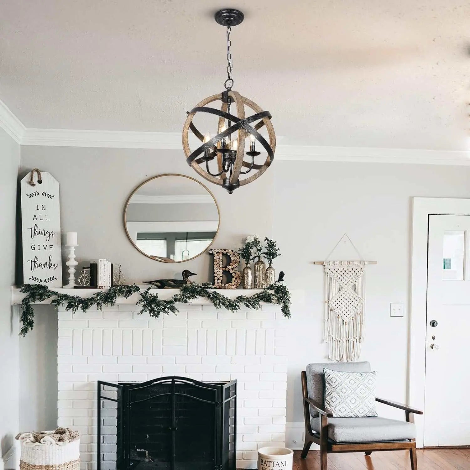 Rustic farmhouse chandelier lamps with adjustable height and wood-metal design hanging in cozy living room above fireplace mantel with greenery decor