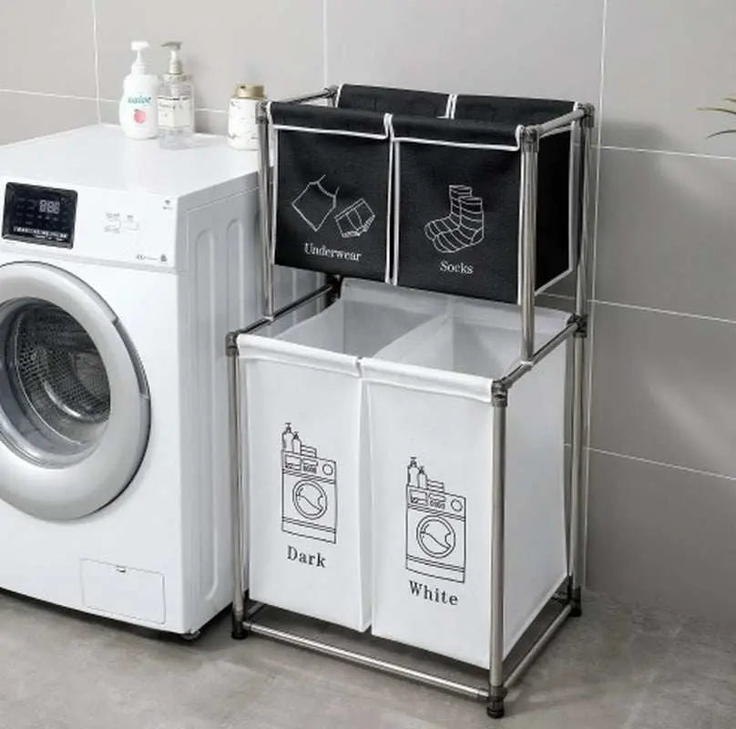 Laundry hamper 2 tier sorter with four removable labeled bags for organizing underwear, socks, dark and white clothes next to washing machine.