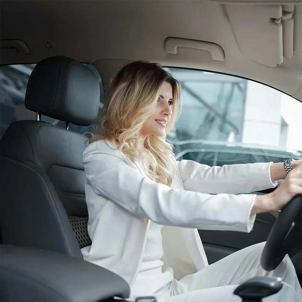 Woman driving car with memory foam lumbar support pillow on seat for back pain relief and improved posture