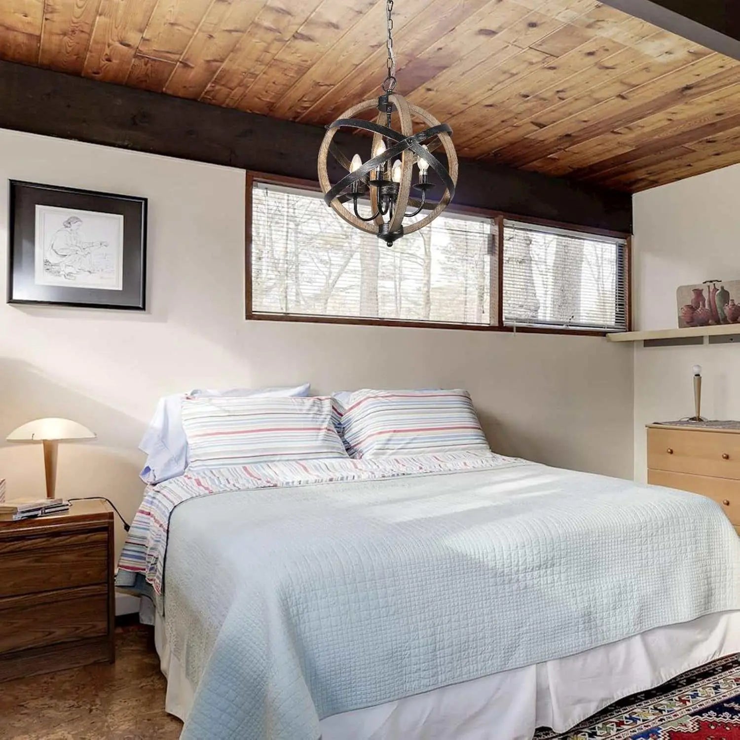 Rustic farmhouse chandelier lamp with wooden sphere frame and black metal chain hanging above bed in cozy bedroom with wooden ceiling and natural light windows