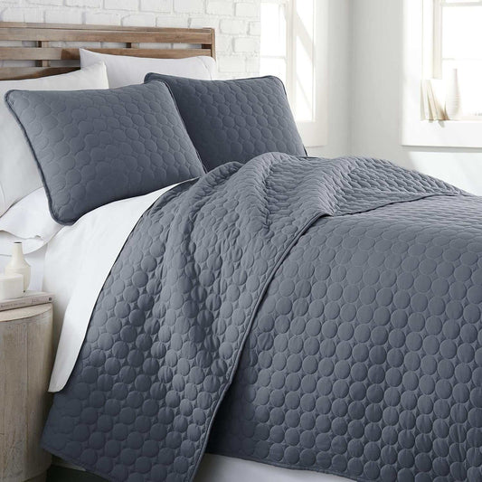 Full queen quilt bedding set in blue with circle stitching, including quilt and matching pillow shams on a bed.
