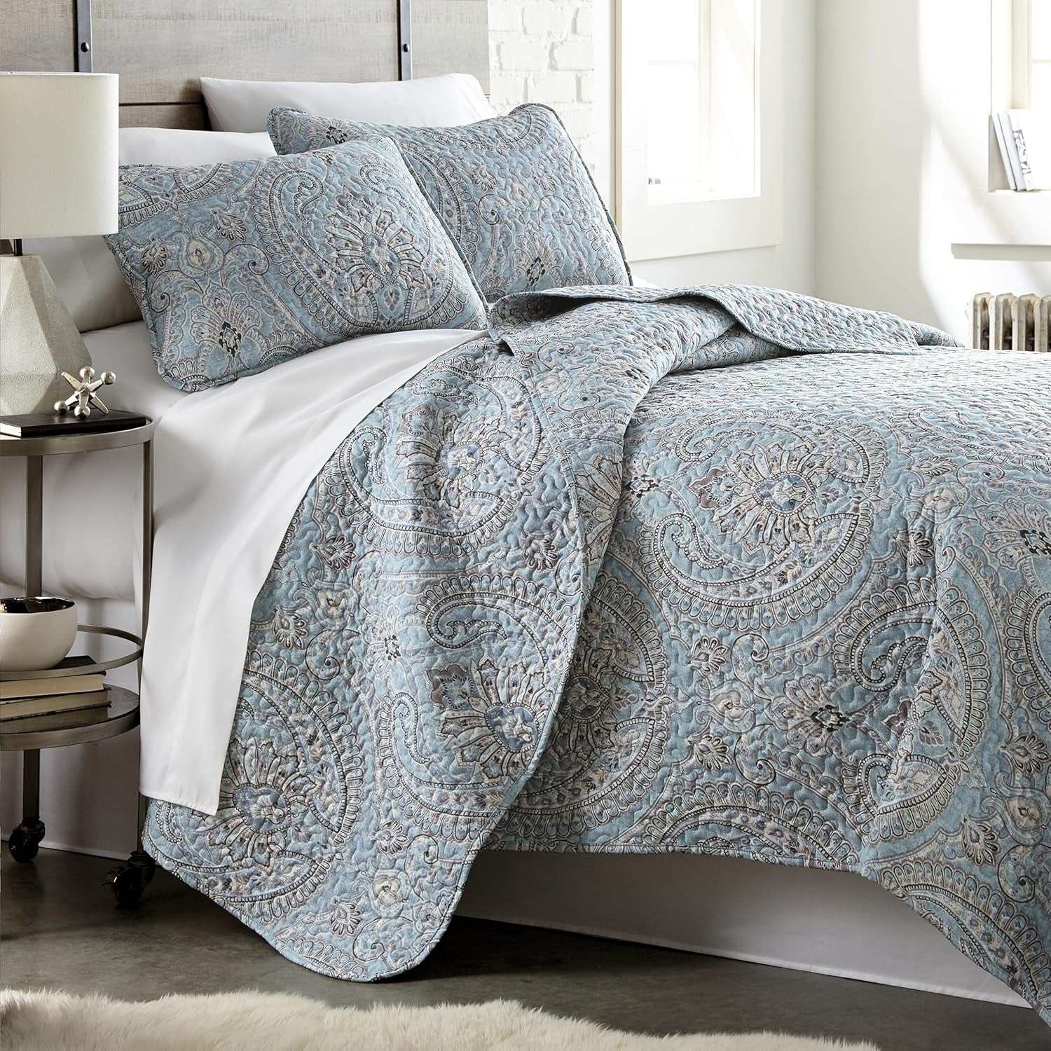 Twin XL paisley boho quilt set with coordinating pillow shams on a bed in a bright bedroom