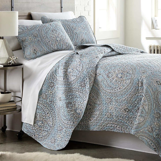 Twin XL paisley boho quilt set with coordinating pillow shams on a bed in a bright bedroom