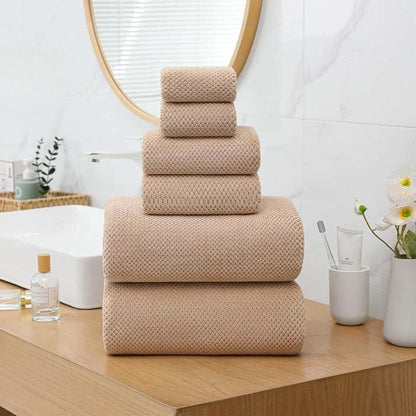 Extra large beige bath towels set with waffle pattern stacked on wooden bathroom counter next to sink and mirror