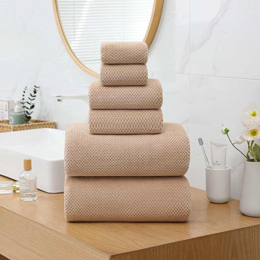 Extra large beige bath towels set with waffle pattern stacked on wooden bathroom counter next to sink and mirror