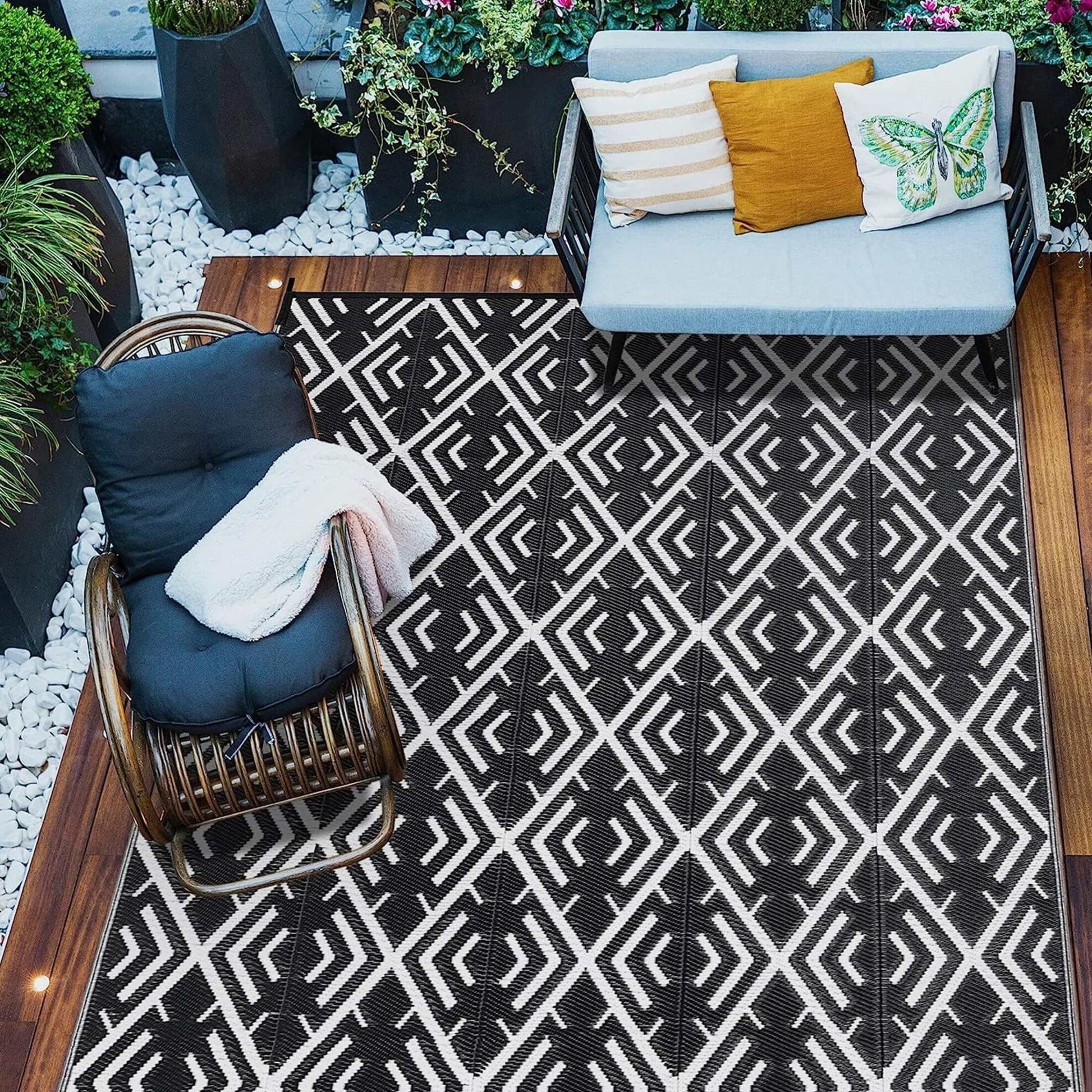 Black and white geometric outdoor patio rug on wooden deck with chair and sofa seating