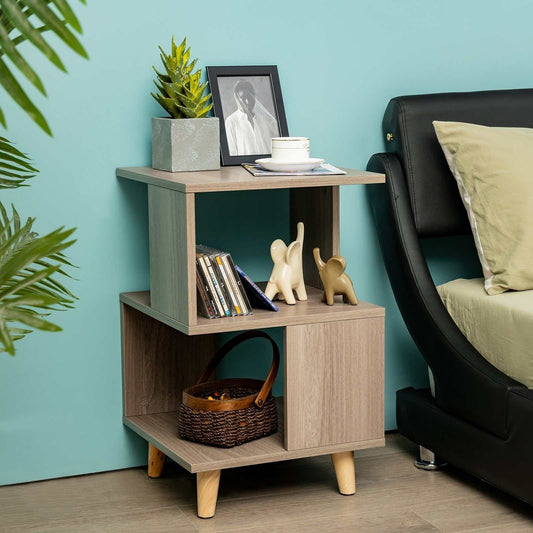 Wooden modern nightstand with asymmetrical design, open shelves, and solid wood legs beside black sofa in living room