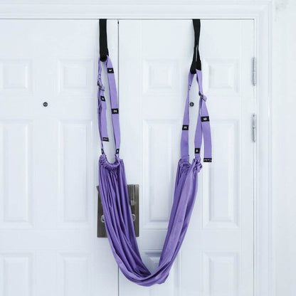 Purple fitness hip stretch yoga belt hanging on white double doors for inverted rope pull and lower waist training