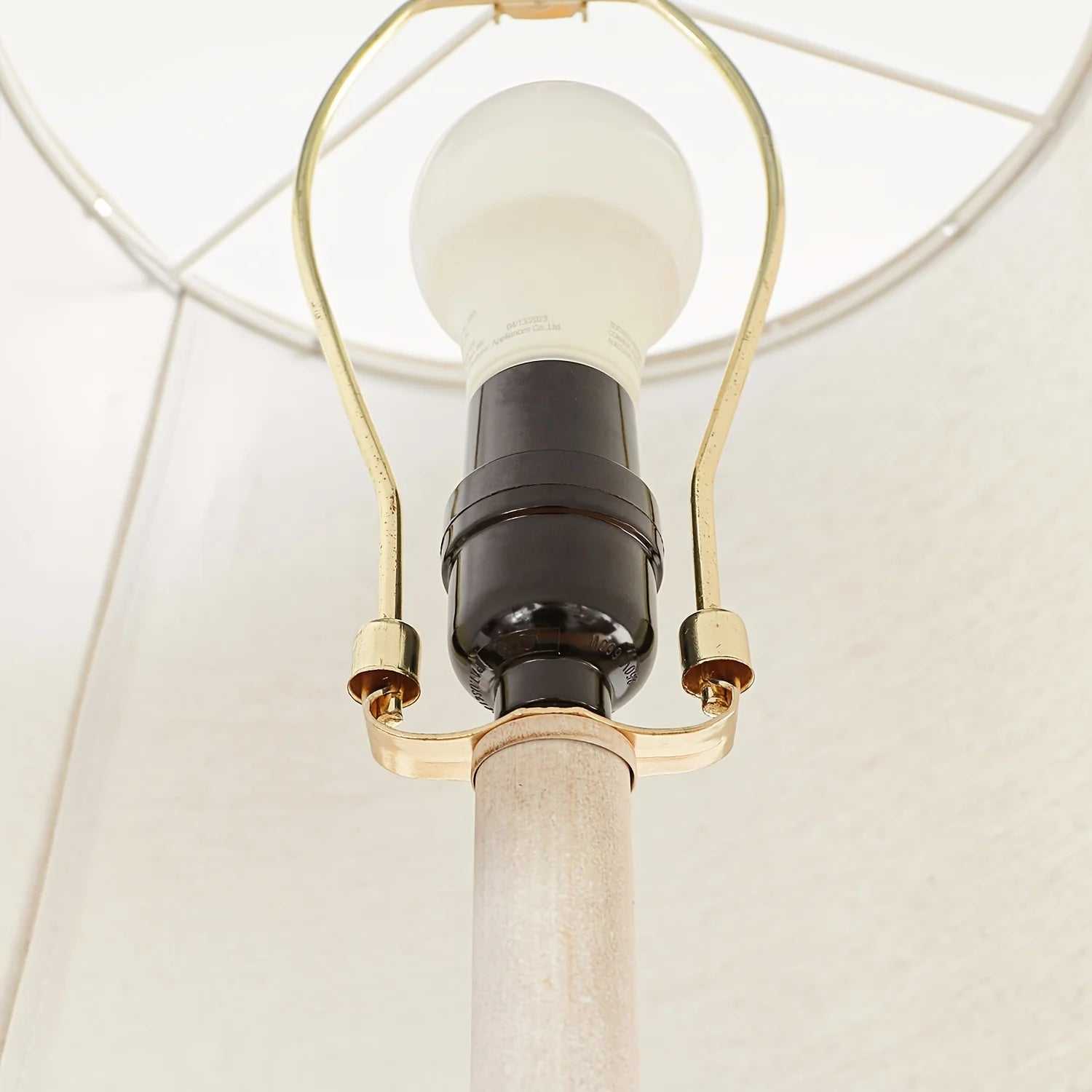 Close-up of a coastal candlestick table lamp with LED bulb and white fabric shade interior
